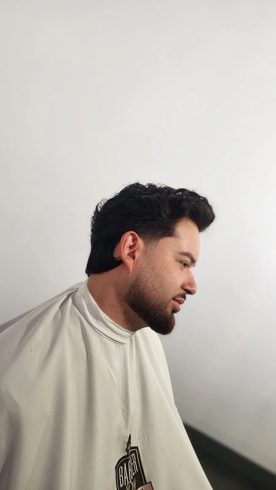 Cliente de perfil com corte e barba alinhados