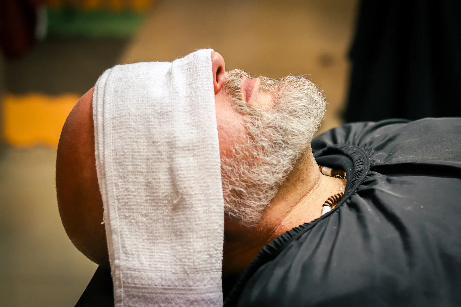 Cliente durante preparação da barba com toalha no rosto